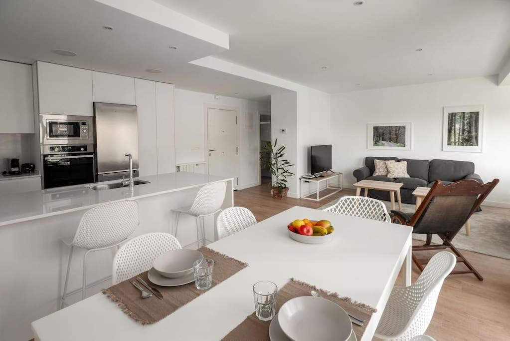 a white kitchen and living room with a table and chairs at Bright apartment with A/C, parking optional in San Sebastián
