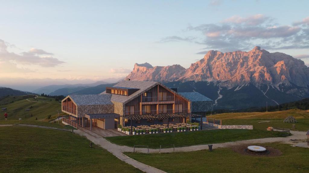 a house on a hill with mountains in the background at Rifugio Alpino Pralongià in Corvara in Badia