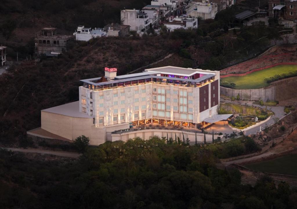 a large building on a hill with a city at jüSTa Sajjangarh Resort & Spa, Udaipur in Udaipur