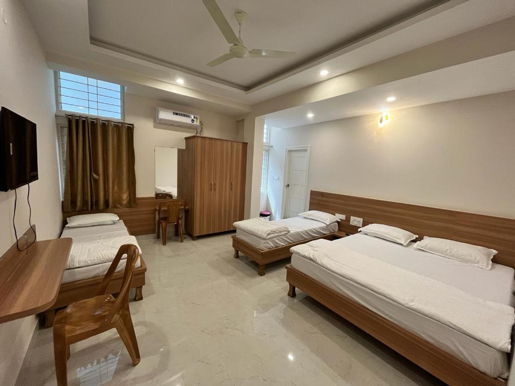 a bedroom with two beds and a desk and a television at Seema Palace Inn in Mysore