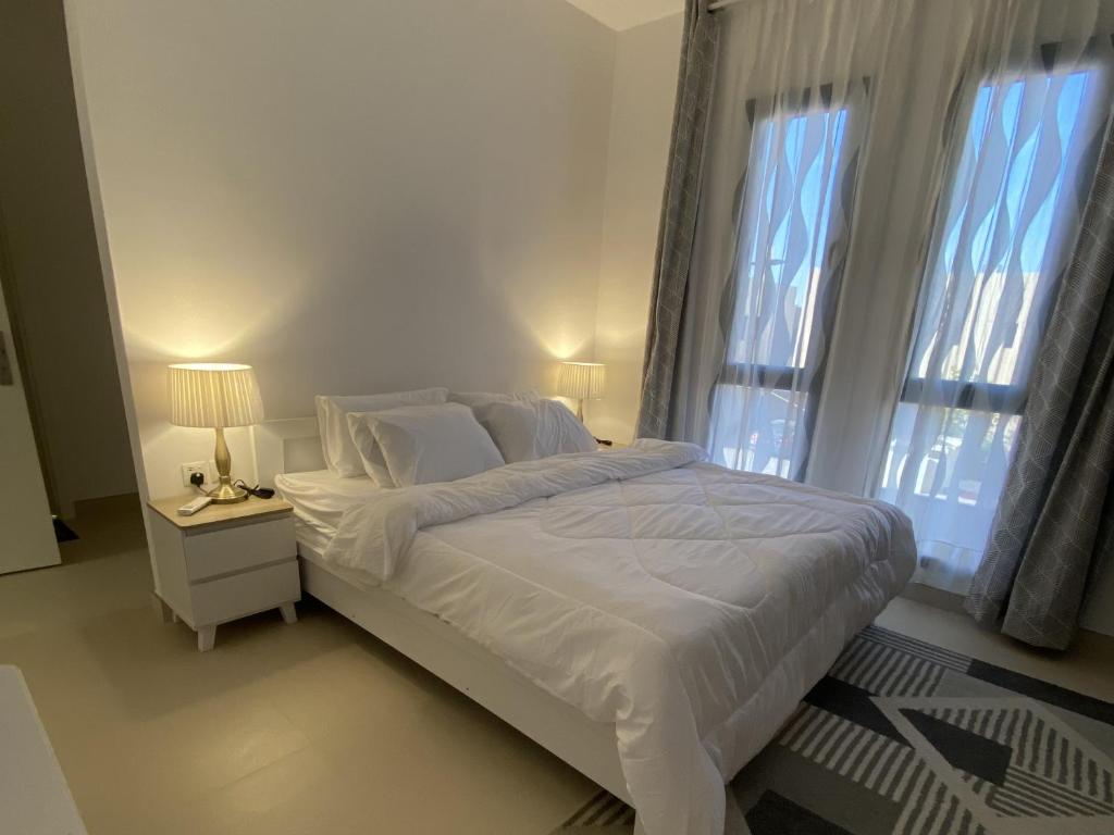 a white bedroom with a bed and two windows at Sidrah House in Riyadh