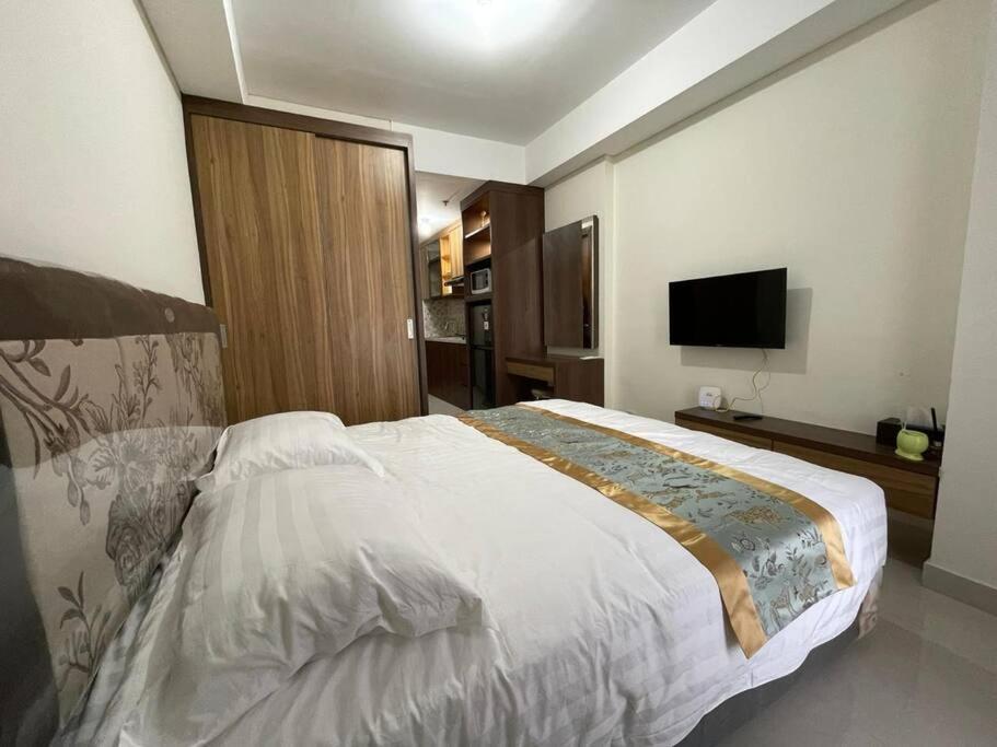 ein Schlafzimmer mit einem großen Bett und einem Flachbild-TV in der Unterkunft Cozy Studio Unit in Casaren in Batam Center