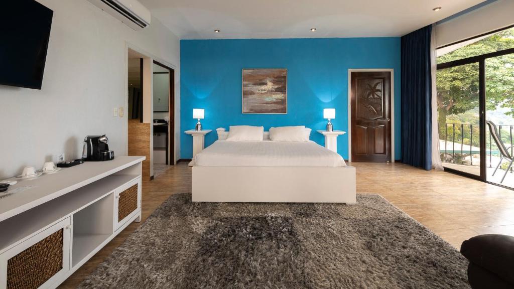 a bedroom with a bed and a blue wall at Blue Mirador Hotel Manuel Antonio in Manuel Antonio