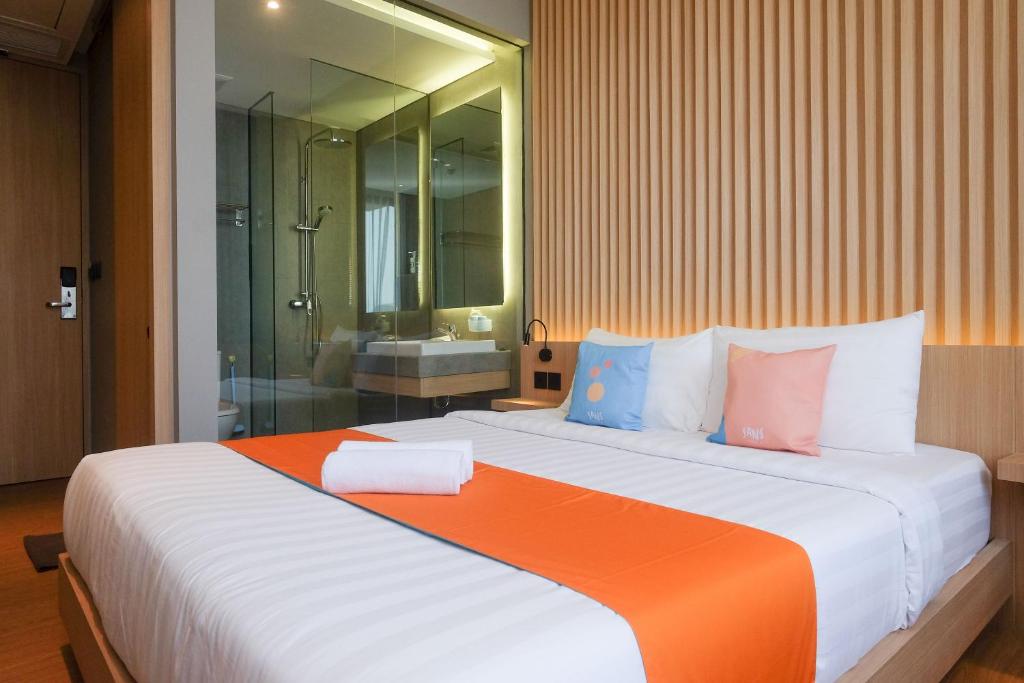 a bedroom with a large bed with an orange and white at Sans Hotel RG Living Jogja by RedDoorz in Demangan