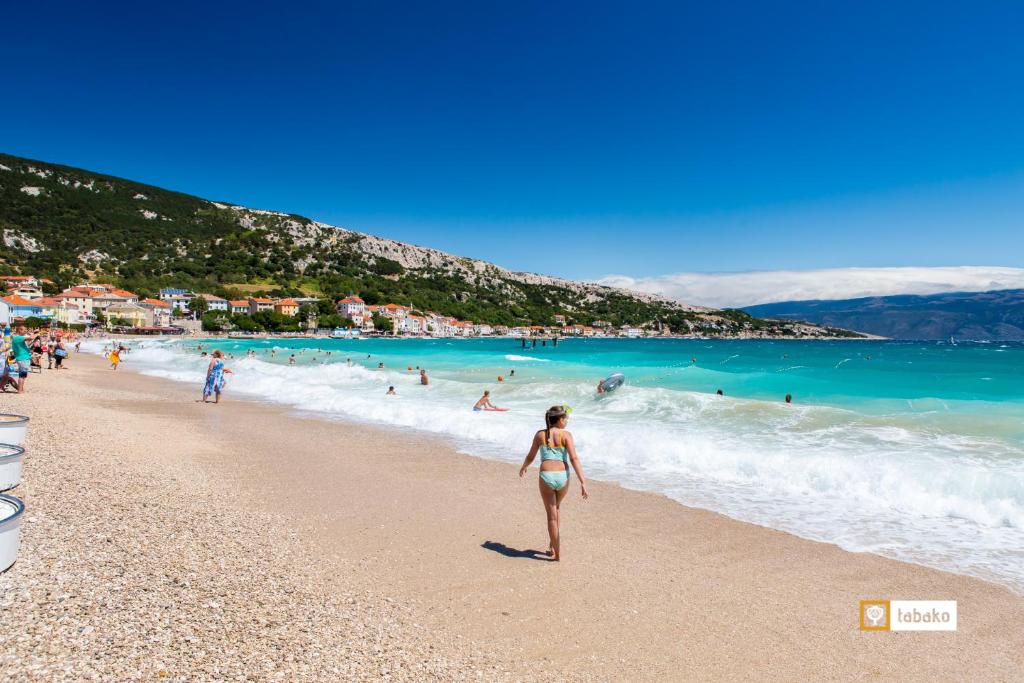 a woman in a bikini walking on a beach at Villa Valis in Baška