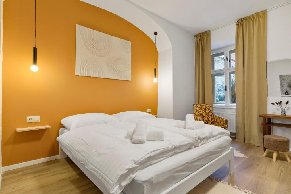 1 dormitorio con 1 cama blanca grande y pared de color naranja en Charming Apt in Centre /w AC, en Bratislava