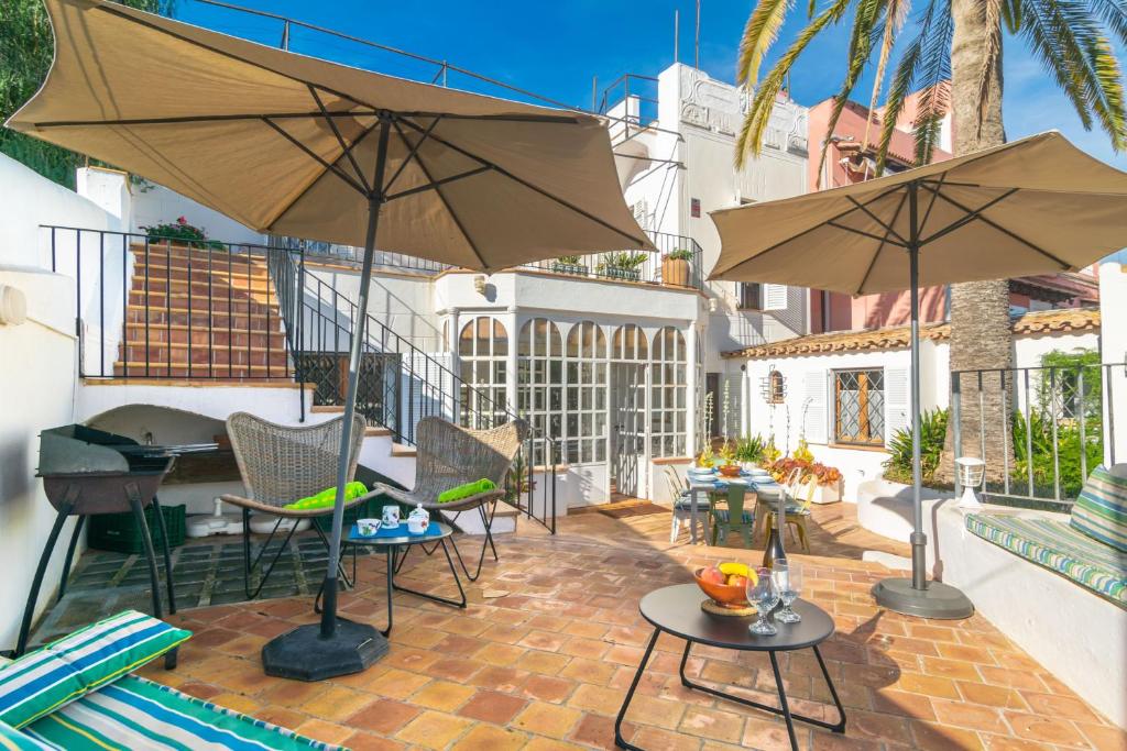 un patio con 2 sombrillas, una mesa y sillas en Villa El Terreno, en Palma de Mallorca