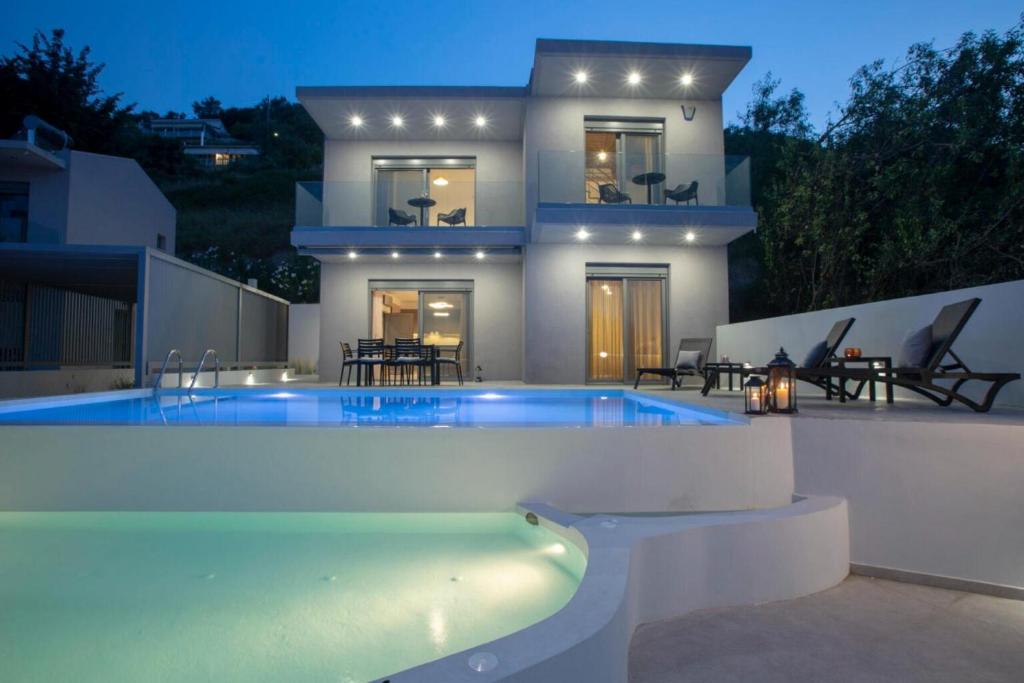 una villa con piscina di fronte a una casa di Aloft Luxury Villas with heated pool and sea view ad Apólpaina