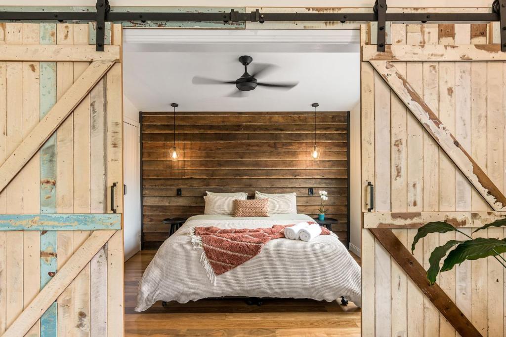 a bedroom with a bed with a wooden wall at Forget Me Not Farm Cottages in Coopers Shoot