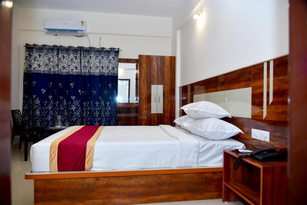 a bedroom with a bed with white sheets and pillows at Prince Recidency in Bangalore