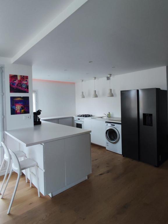 a white kitchen with a counter and a refrigerator at Magnifique appartement proche de Paris et de Disney in Lognes