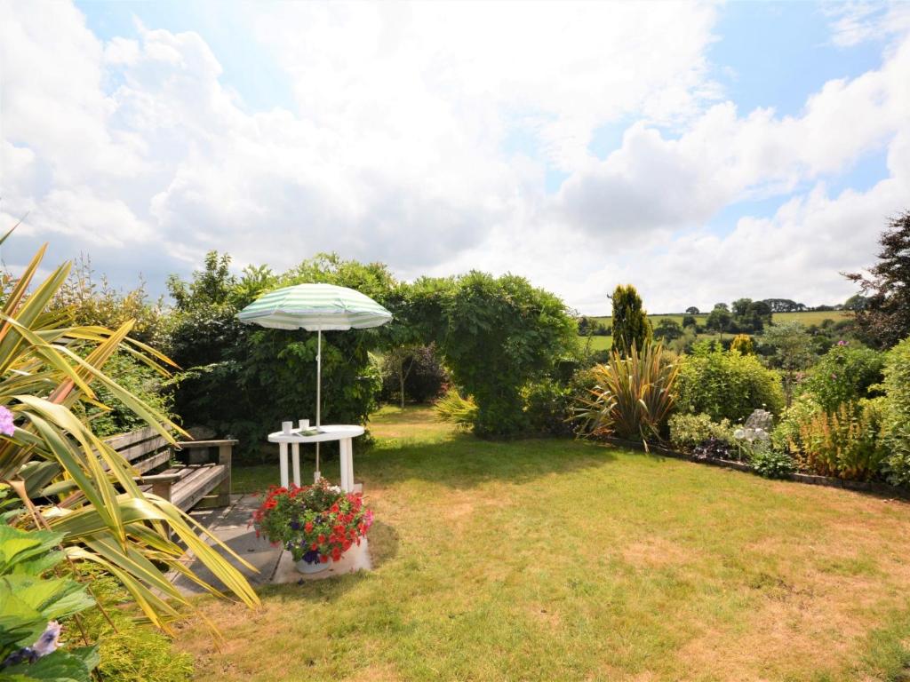 a garden with an umbrella and a bench with flowers at 1 Bed in Tavistock OTWIN in Lamerton