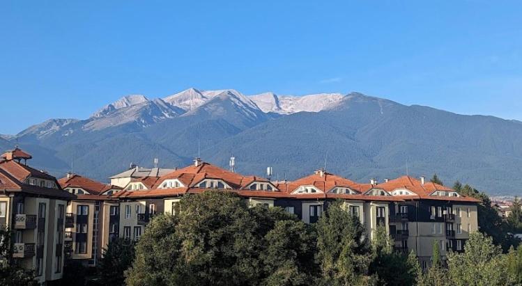 a group of buildings with snow capped mountains in the background at Apartment in Sapphire Residence in Bansko