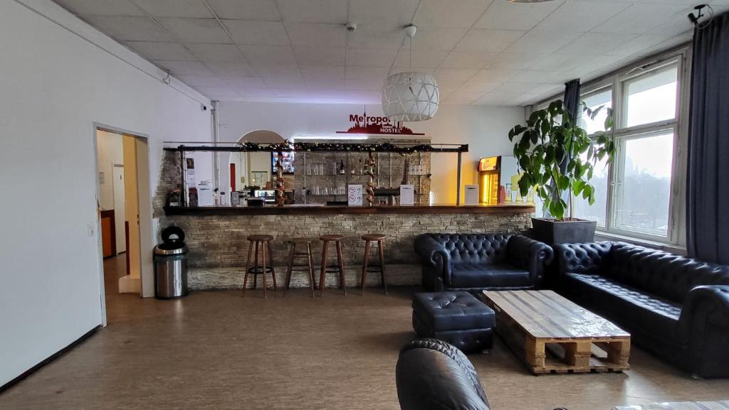 a living room with black leather couches and a bar at Metropol Hostel Berlin in Berlin