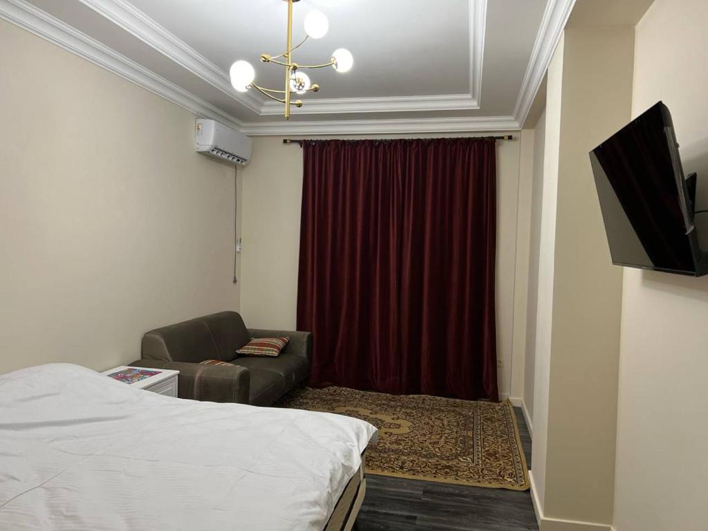 um quarto com uma cama, um sofá e uma televisão em Mirabad City - 2 em Yakkasaray