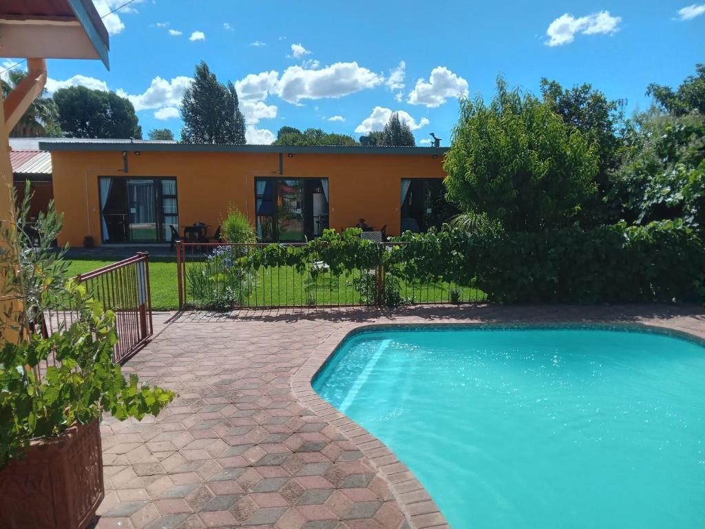 a swimming pool in front of a house at SONHOS dreams Self catering Garden Cottages in Bloemfontein