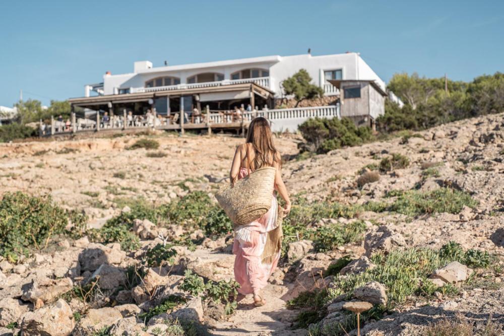 a woman walking up a hill in front of a house at Hostal La Torre Ibiza Cap Negret in San Antonio