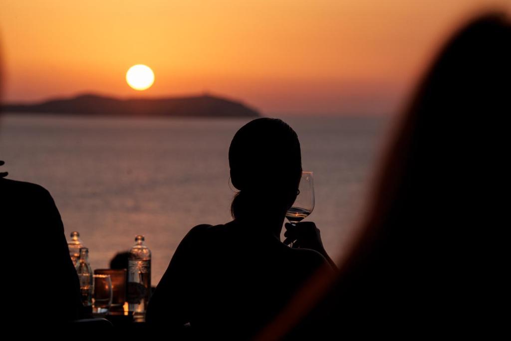 a woman drinking a glass of wine at sunset at Hostal La Torre Ibiza Cap Negret in San Antonio