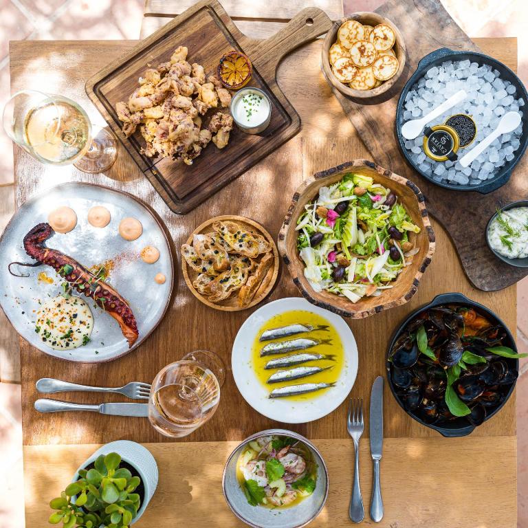 a wooden table with plates of food on it at Hostal La Torre Ibiza Cap Negret in San Antonio
