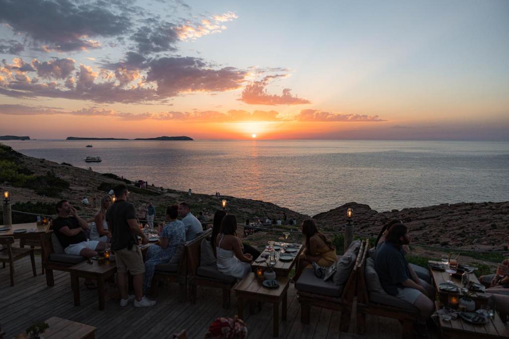 a group of people sitting at tables watching the sunset at Hostal La Torre Ibiza Cap Negret in San Antonio
