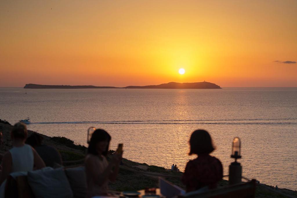 a group of people watching the sunset over the ocean at Hostal La Torre Ibiza Cap Negret in San Antonio