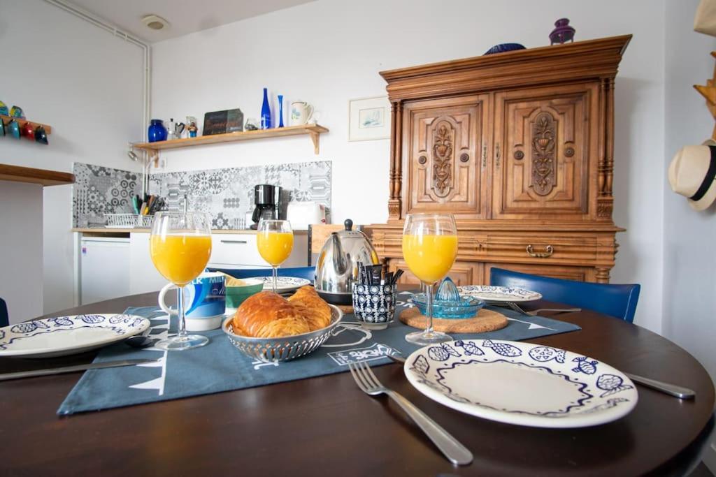 una mesa con platos y vasos de zumo de naranja en Appart' confort Les Maôves Parking privé, en Étretat
