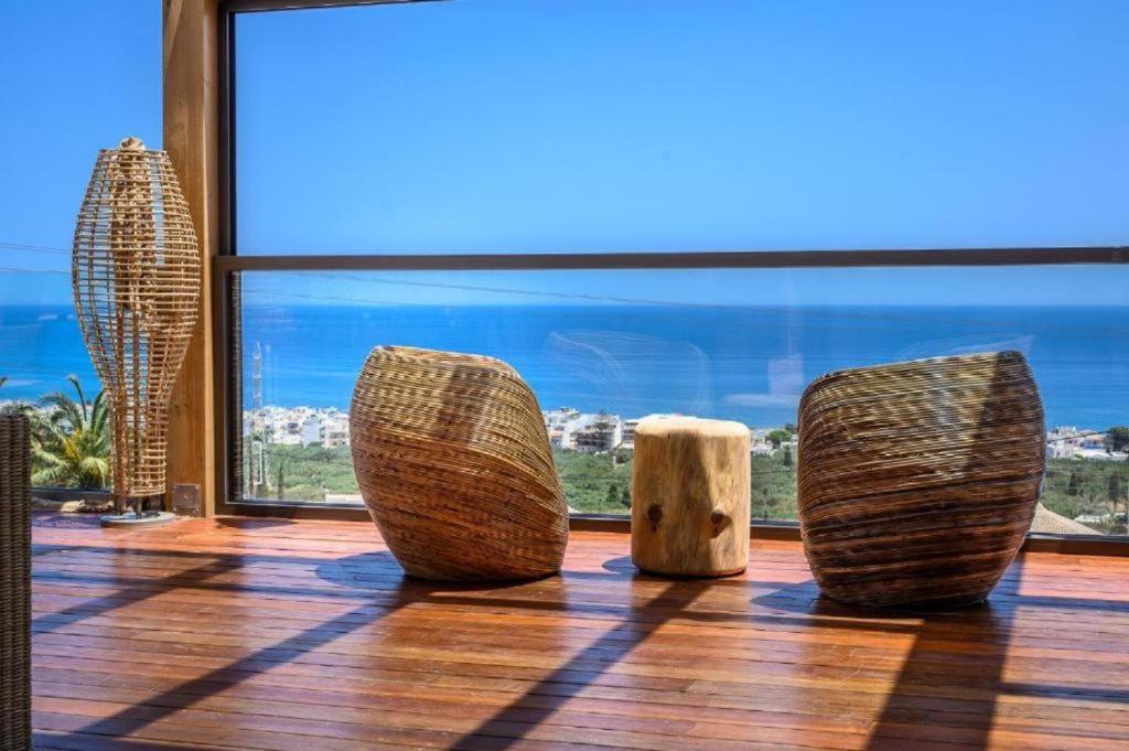 three wooden sculptures sitting on a wooden floor in front of a window at Esperides Resort Crete, The Authentic Experience in Hersonissos