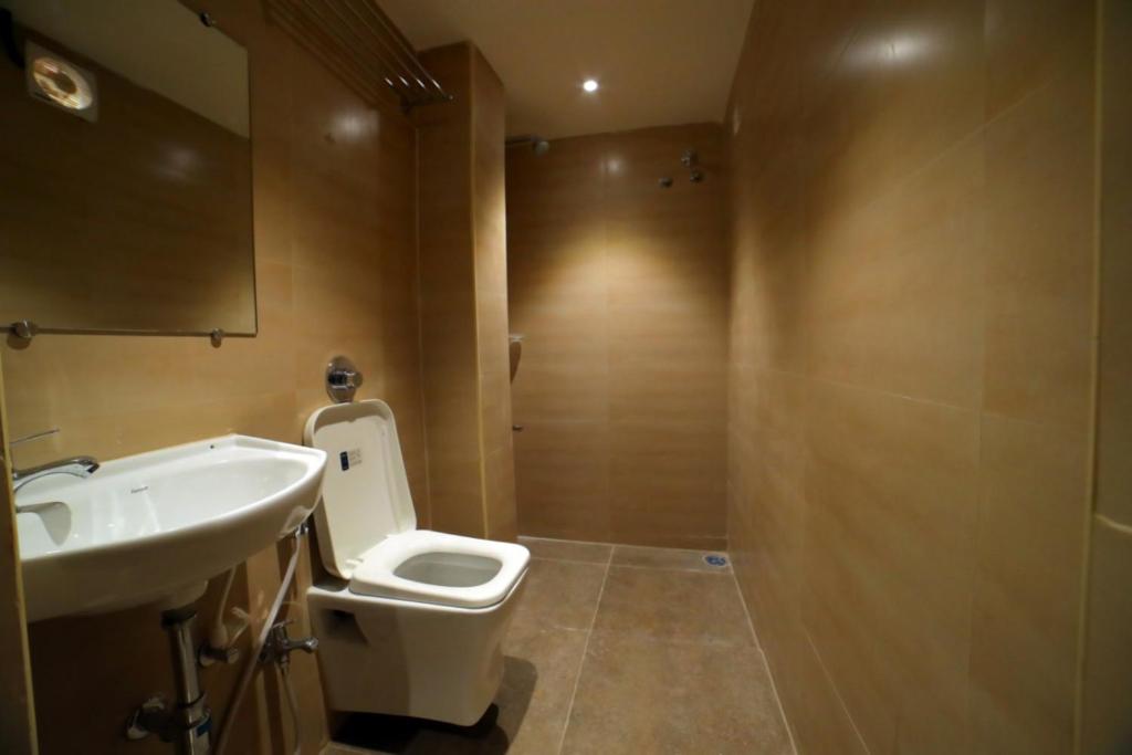a bathroom with a white toilet and a sink at beeStay Hotels MG Road Vijayawada in Vijayawāda