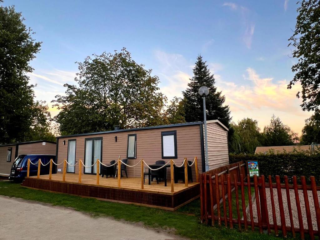 a mobile home with a deck and a fence at Rêve d'été - Camping Belle-Vue 2000 in Berdorf