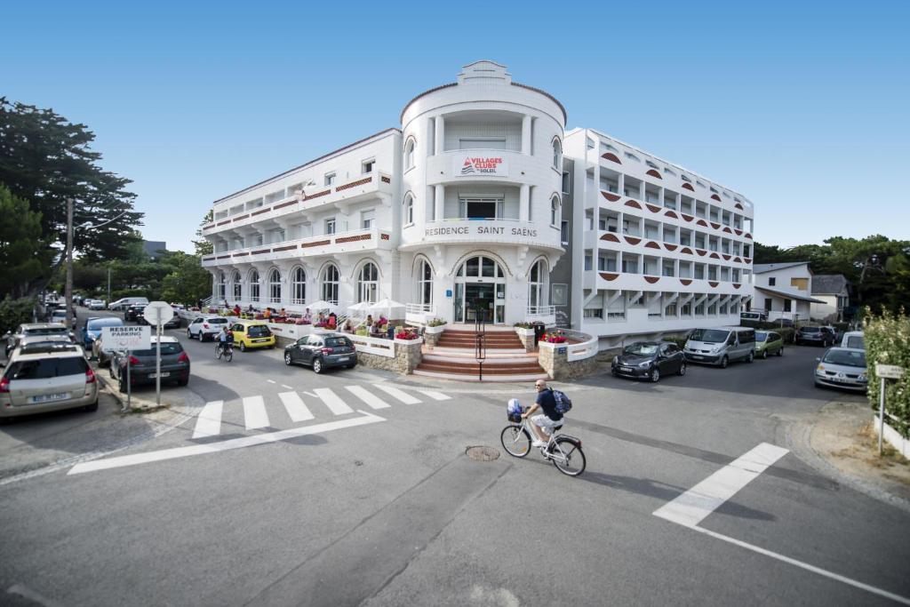 una persona montando una bicicleta delante de un edificio blanco en Villages Clubs du Soleil - LA BAULE, en La Baule