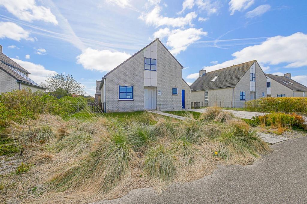 a house on the side of a hill with grass at Villa Mooy met sauna - Landal park Ooghduyne Julianadorp aan Zee in Julianadorp