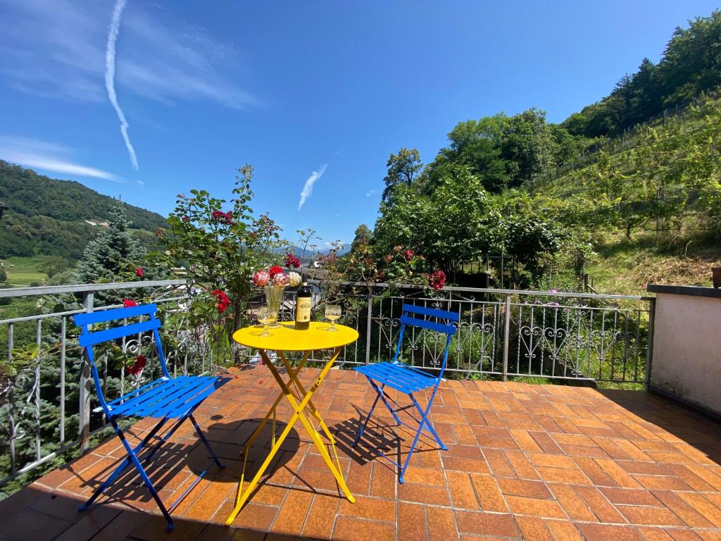 een gele tafel en twee blauwe stoelen op een patio bij Casa Bellavista in Lugano