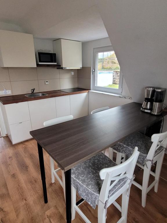 cocina con mesa de madera y sillas blancas en Apartment Ferienwohnung Steigwaldweg, en Würzburg