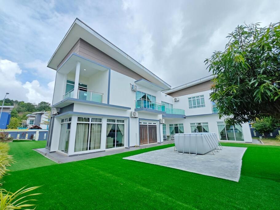 uma grande casa branca com um relvado verde em Marinea 2, The Inspaze by Antlerzone em Kota Tinggi