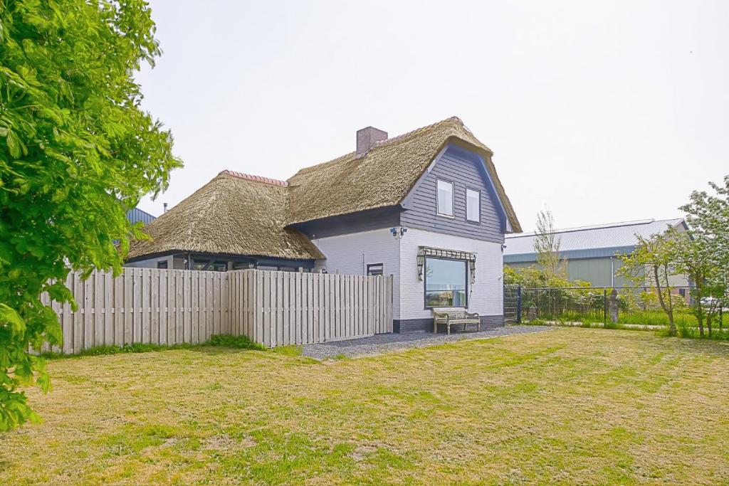 una casa con una valla delante de un patio en Villa Pakhuys - groepsaccommodatie - Julianadorp aan Zee, en Den Helder