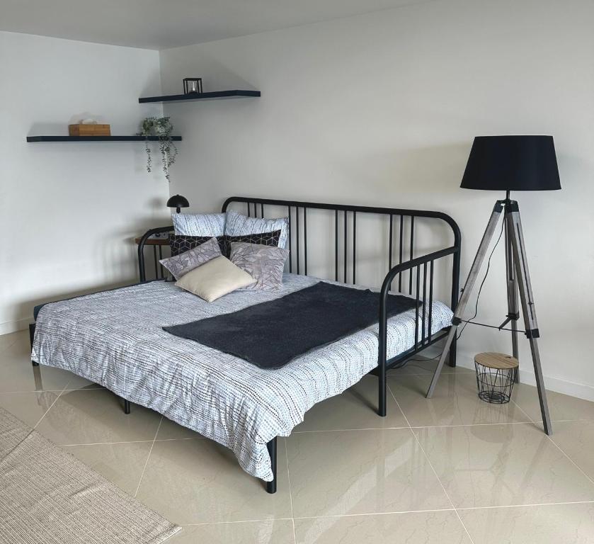 Dormitorio con cama con marco negro y lámpara en Petite Maison studio tout confort cosy Givors autoroute et gare, en Givors