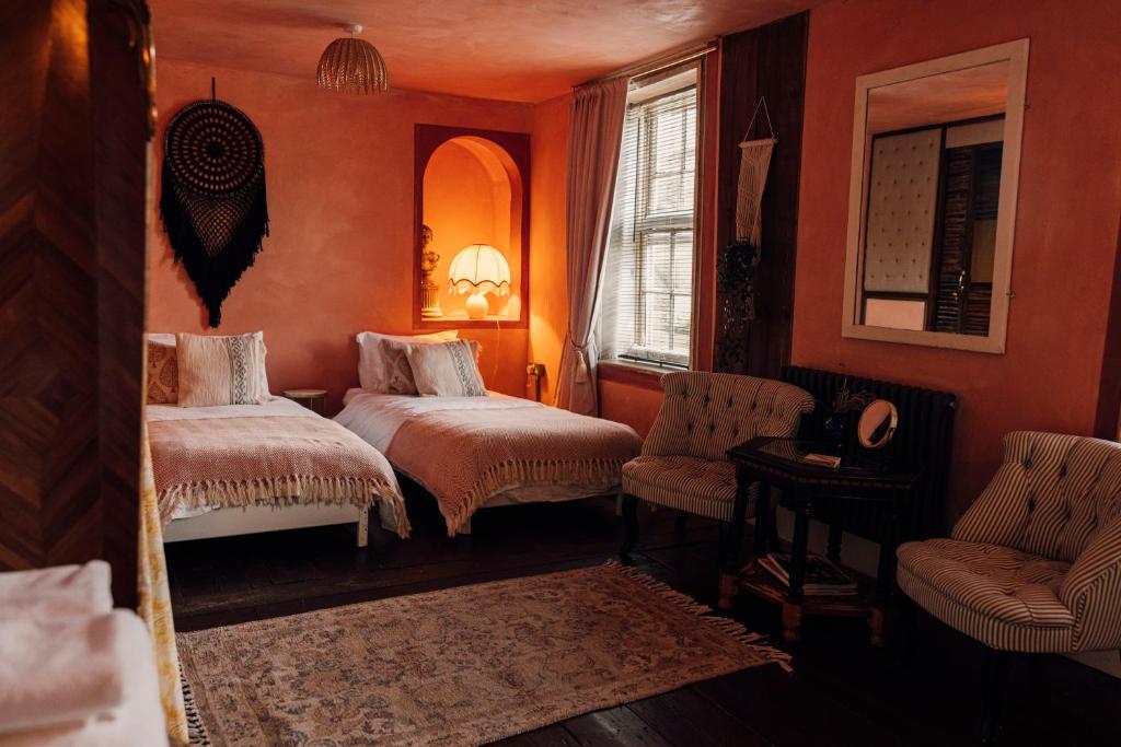 a bedroom with two beds and a chair and a mirror at The George & Heart House in Kent