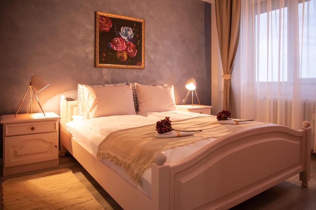 1 dormitorio con 1 cama blanca grande y 2 lámparas en Over the City, en Oradea