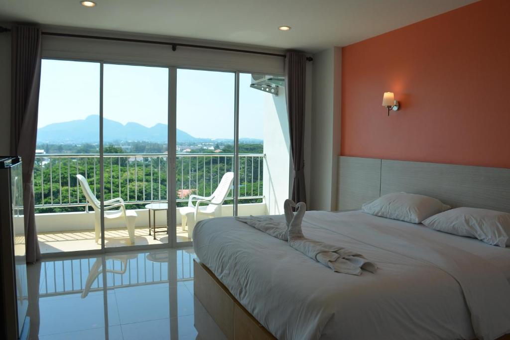 a bedroom with a bed and a balcony with chairs at The Base Hua Hin in Hua Hin