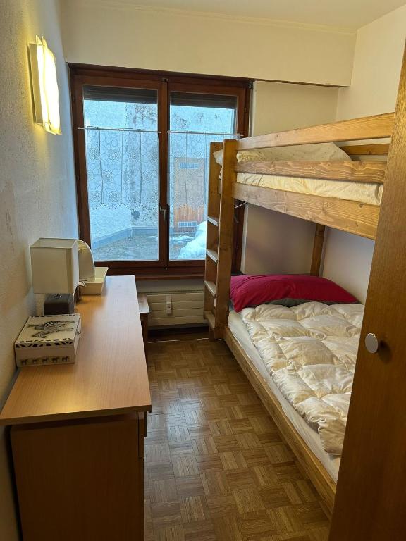 a dorm room with two bunk beds and a desk at Chambre Indépendante Valdor in Crans-Montana