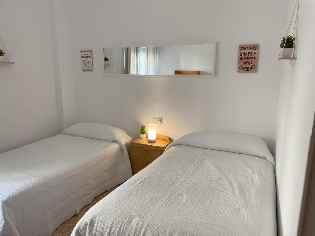 two beds in a white room with a mirror at Piso compartido Delyrent, Safa in Jaén