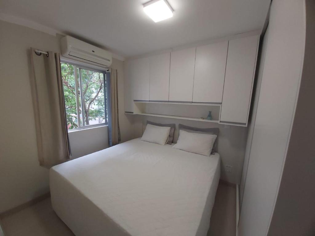 Apartamento Aconchegante في فوز دو إيغواسو: غرفة نوم صغيرة بها سرير أبيض ونافذة
