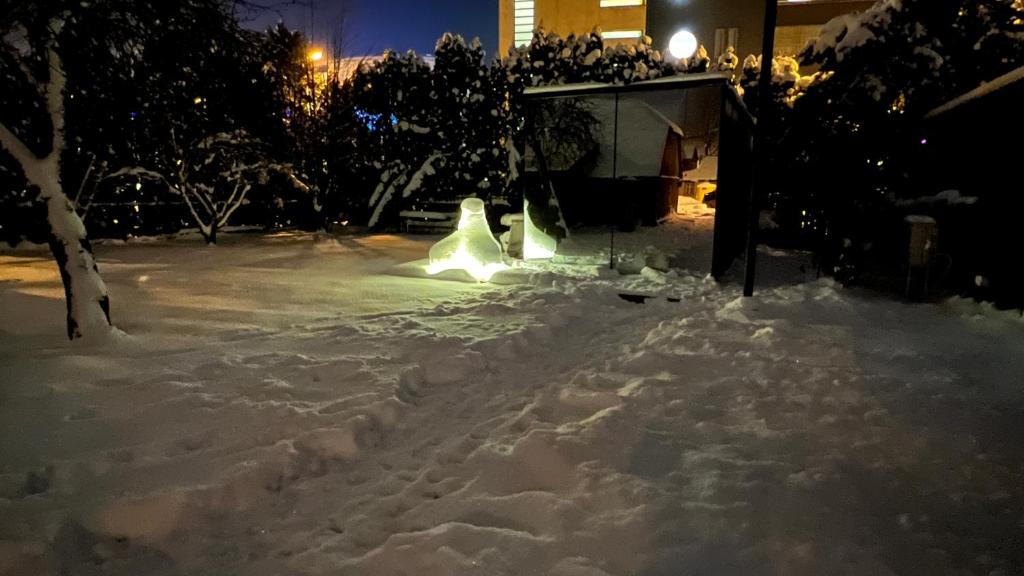 um quintal coberto de neve à noite com luzes em Mirror House Roosi 21 em Pärnu