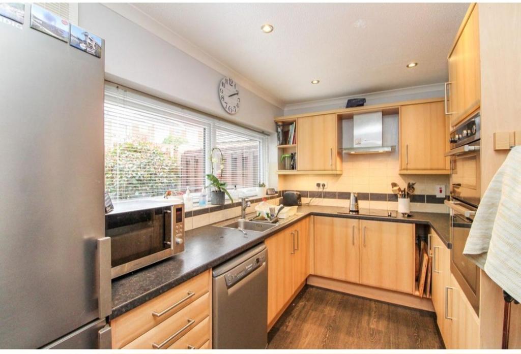 a kitchen with wooden cabinets and a large window at Room in Crawley/Gatwick/West Sussex in Ifield