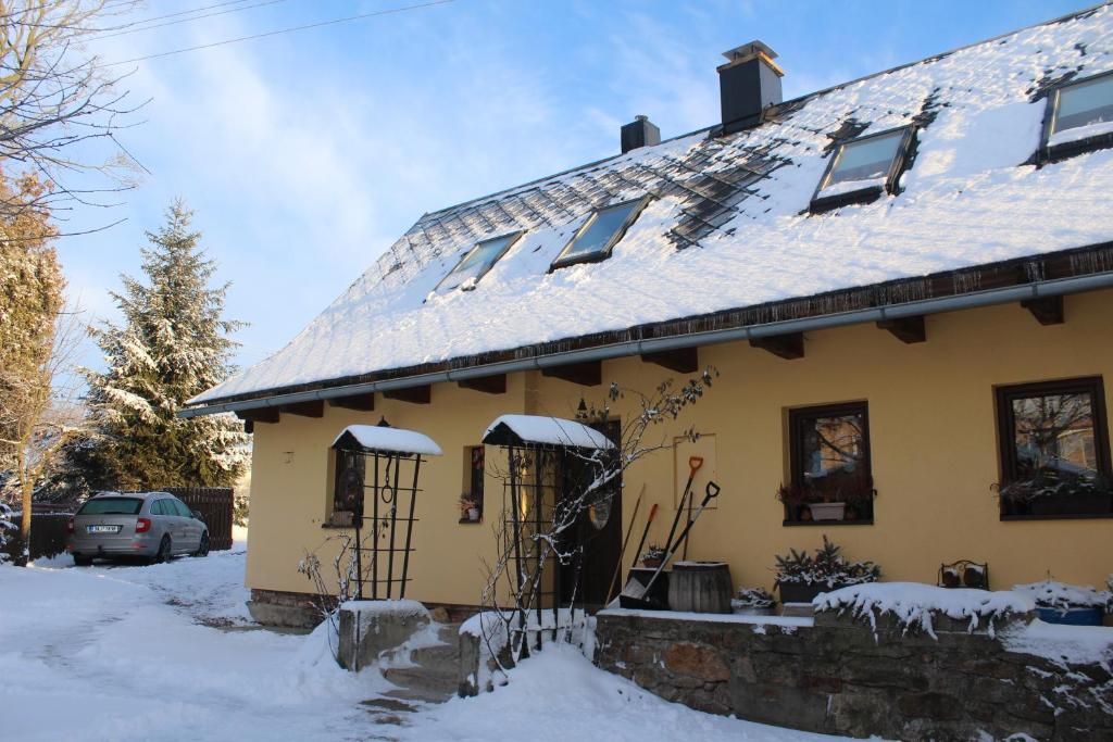 una casa amarilla con techo de estaño en la nieve en Chalupa U potoka, en Červená Voda