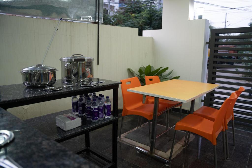 a table with orange chairs and a table with drinks on it at Yellow Bells Gachibowli in Hyderabad