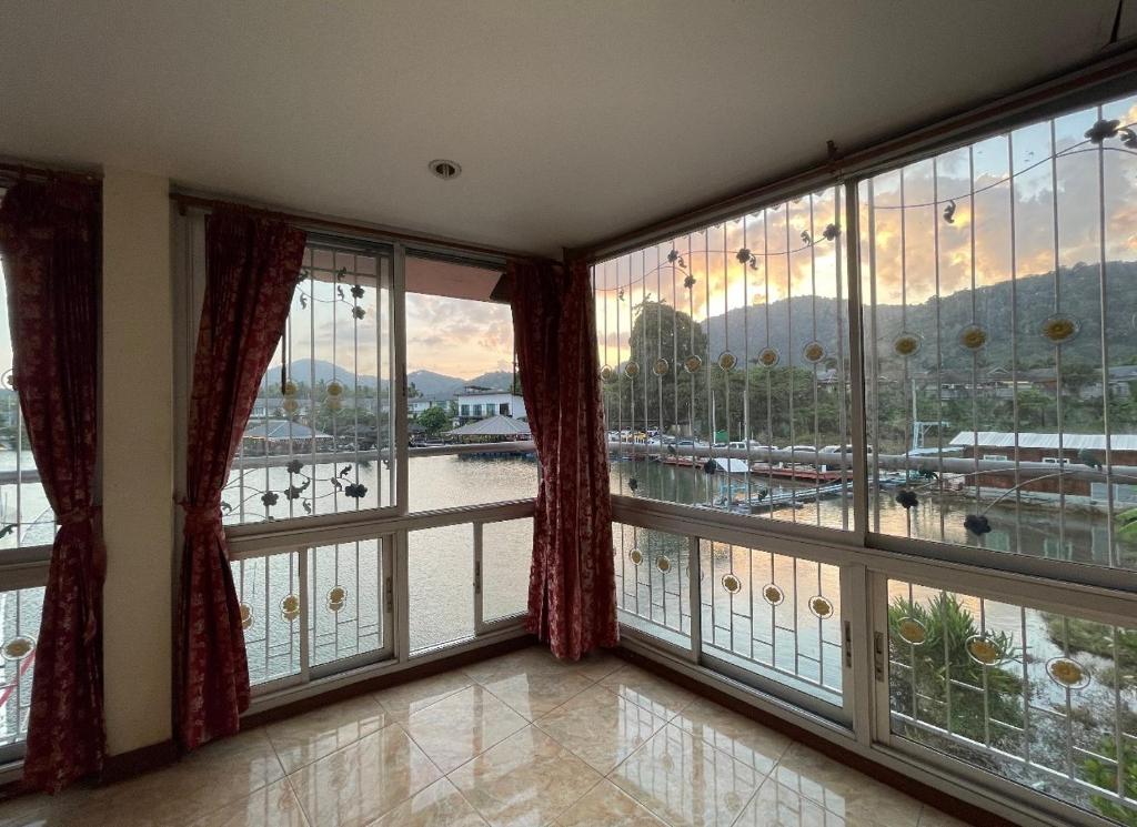 a room with large windows with a view of a harbor at Cozy Home With Lake View at Kathu PHUKET in Ban Huai Luk (1)