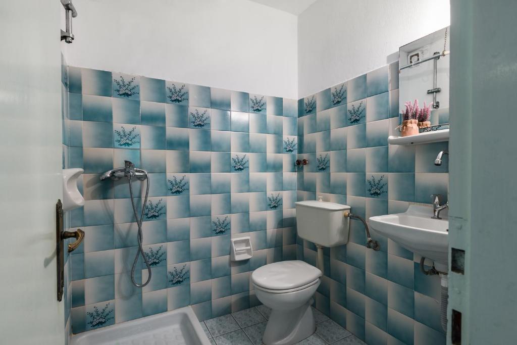 a blue tiled bathroom with a toilet and a sink at Marietta's Resort by Konnect, Gouvia Corfu in Gouvia