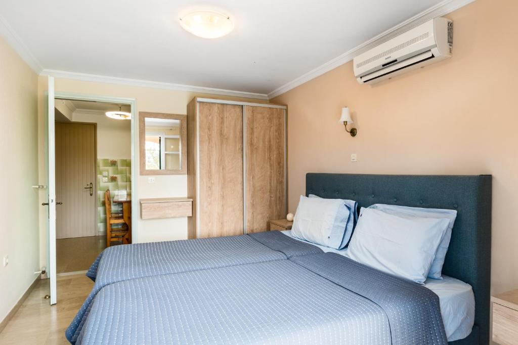 a bedroom with a blue bed with white pillows at Marietta's Resort by Konnect, Gouvia Corfu in Gouvia