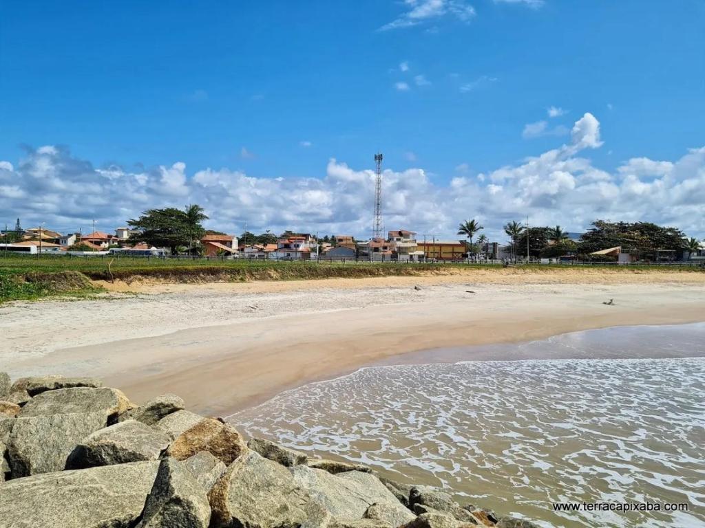 einen Strand mit Felsen im Wasser und Häuser in der Unterkunft Apartamento com Vista para o Mar in Conceição da Barra